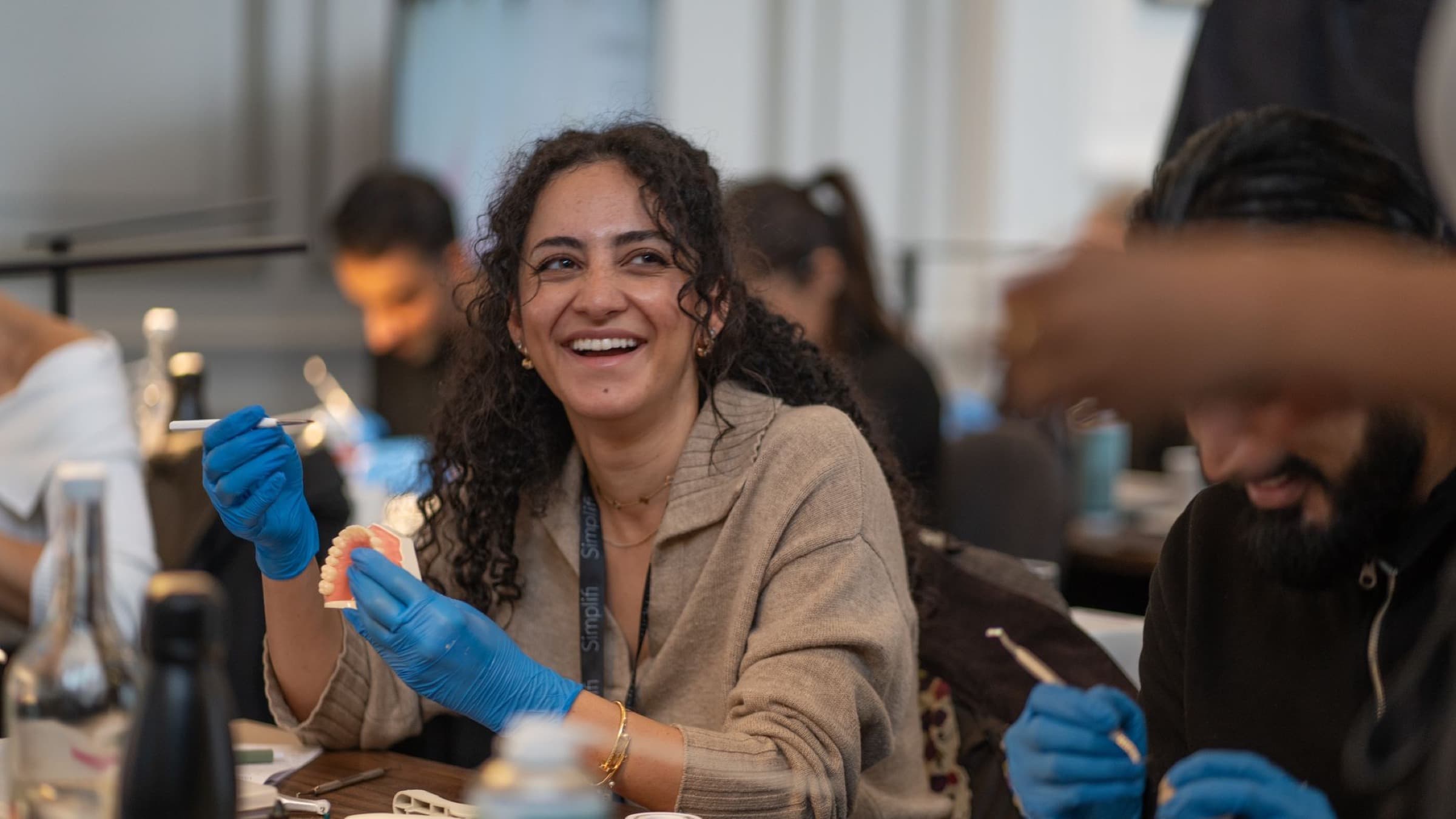 A delegate laughing as she works on a typodont at a Simplifi course